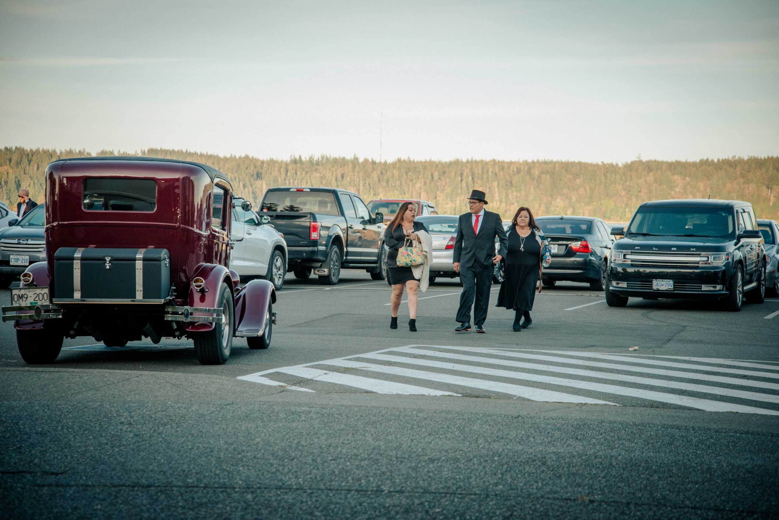 People walking in parking lot with vintage cars