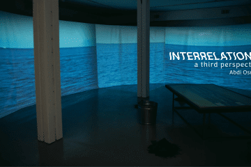 Room with ocean projected on a curve wall, pillars and table in centre of room.